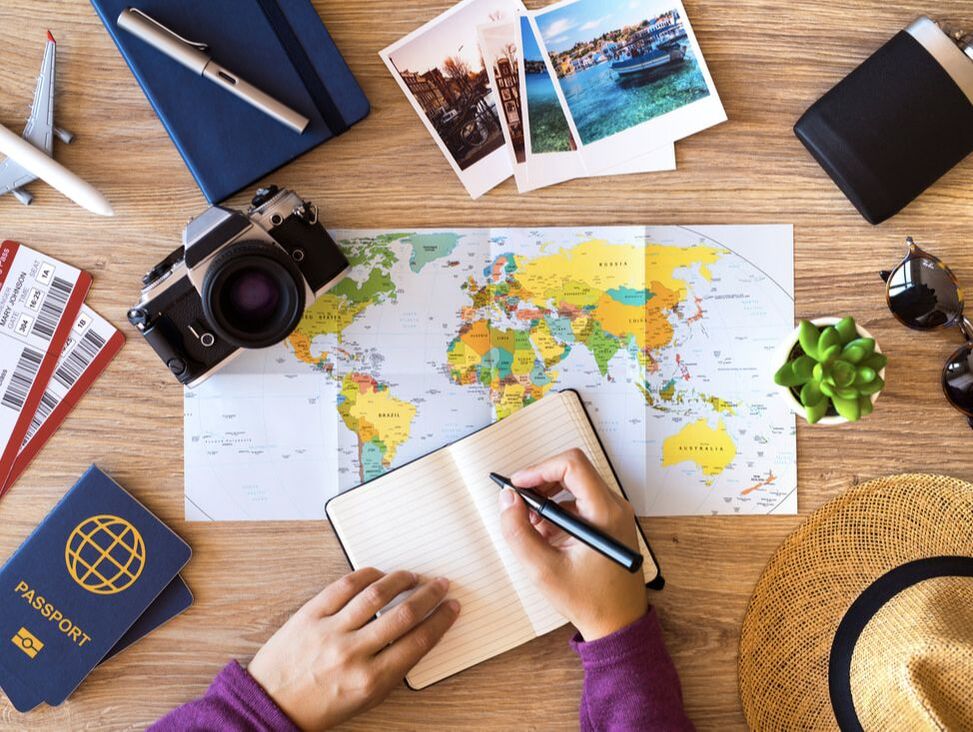 map, camera, passport, and other travel gear laid out on a desk